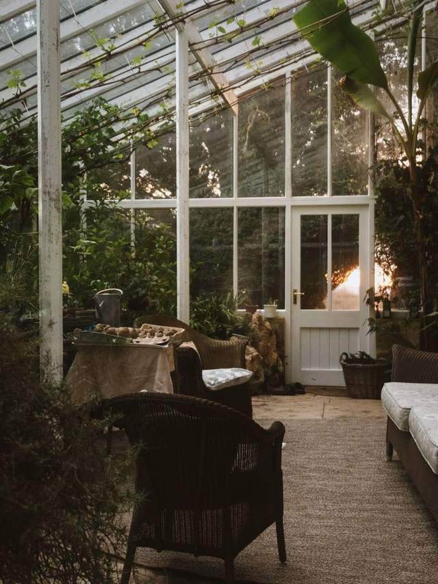 A dusky sunroom with wicker chairs and a glowing doorway